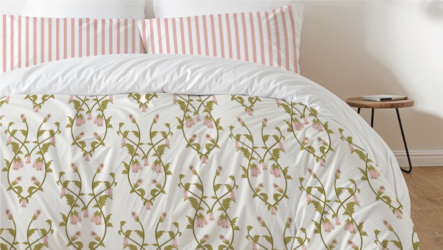 A bed made up with a custom floral comforter and striped pillows